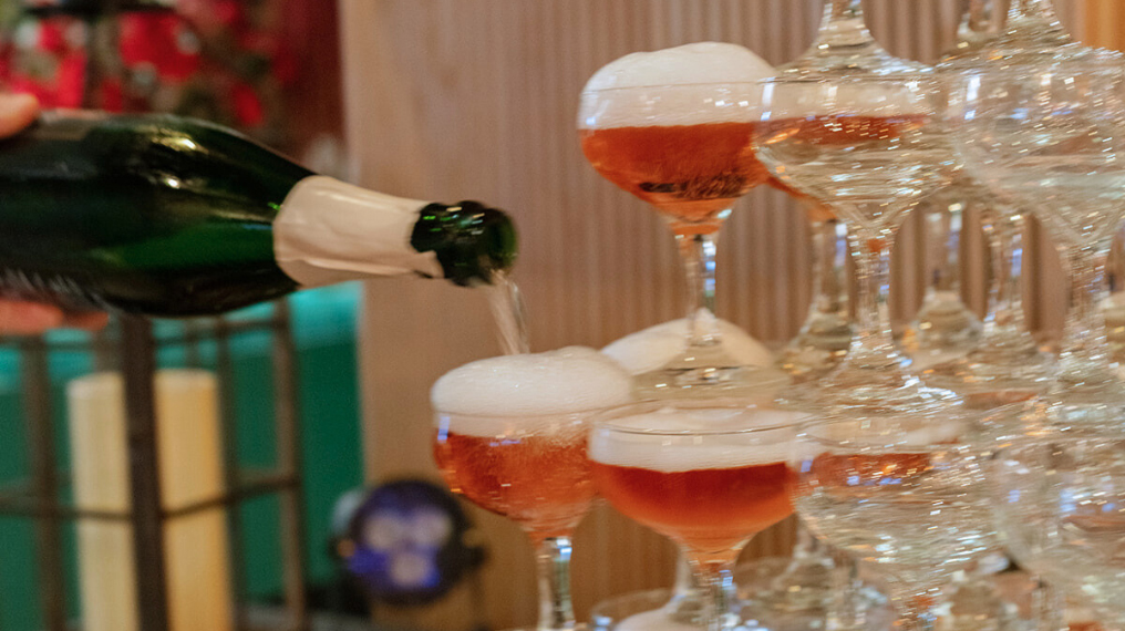 A bottle of Aphrodise being poured into a tower of coupe glasses