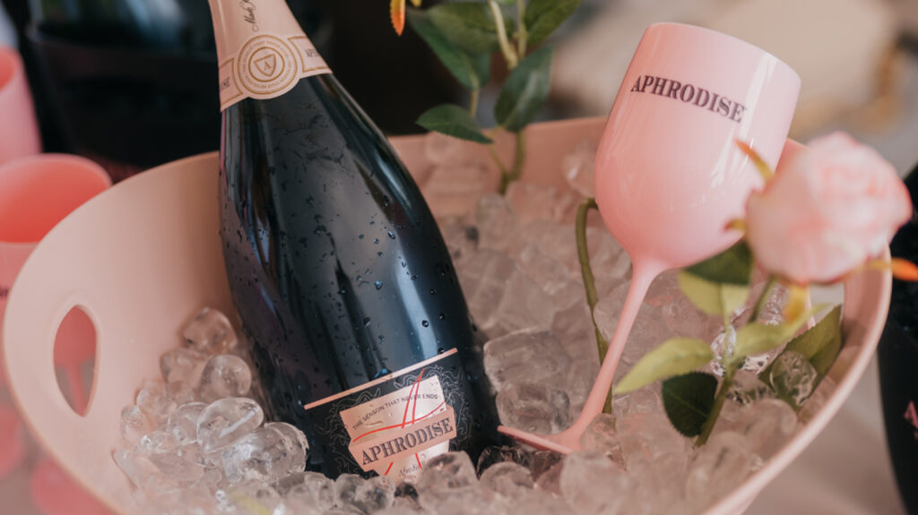 Aphrodise bottle and wine glass sat in an ice bucket decorated with a pink rose (close up)