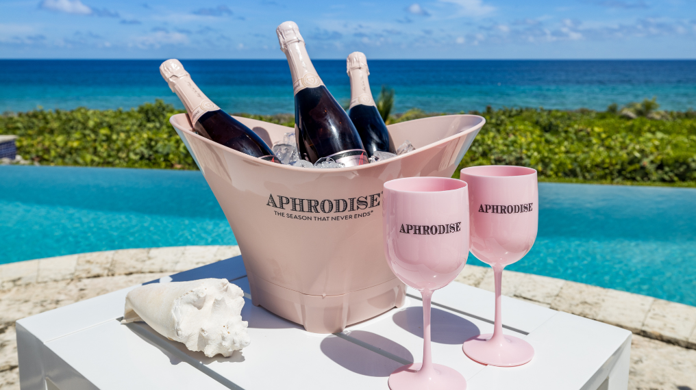 A pink ice bucket with bottles of Aphrodise in front of a pool